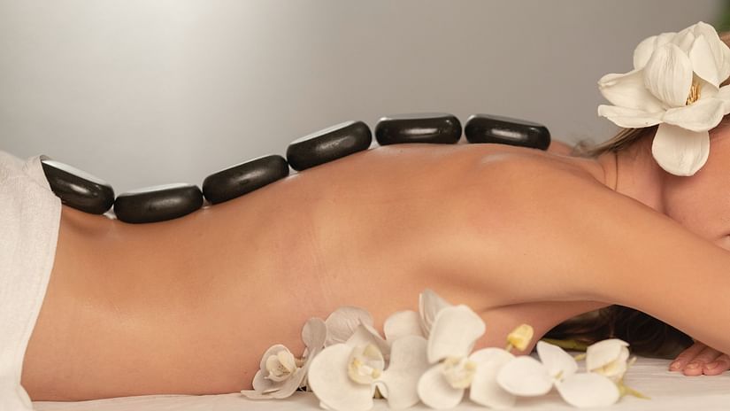 A woman sleeping on her stomach while getting a hot stone massage. 