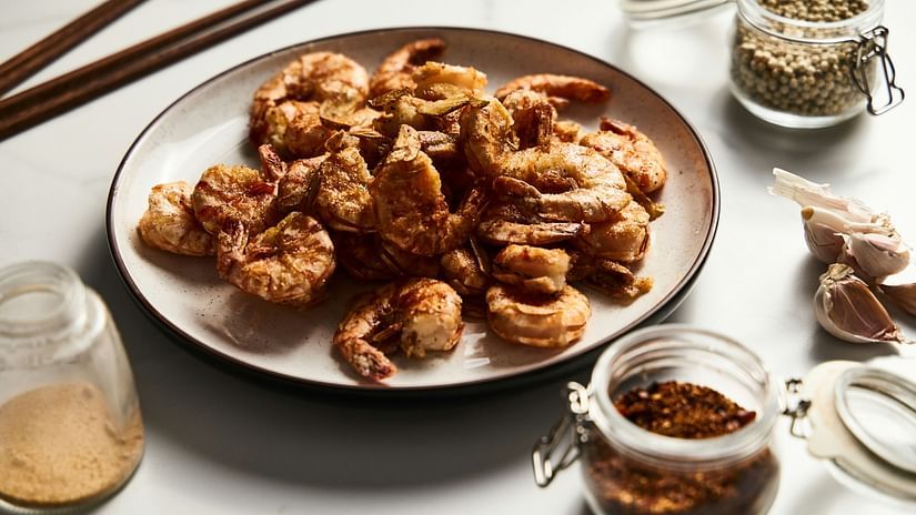 A close up shot of a plate with prawns with other condiments next to it