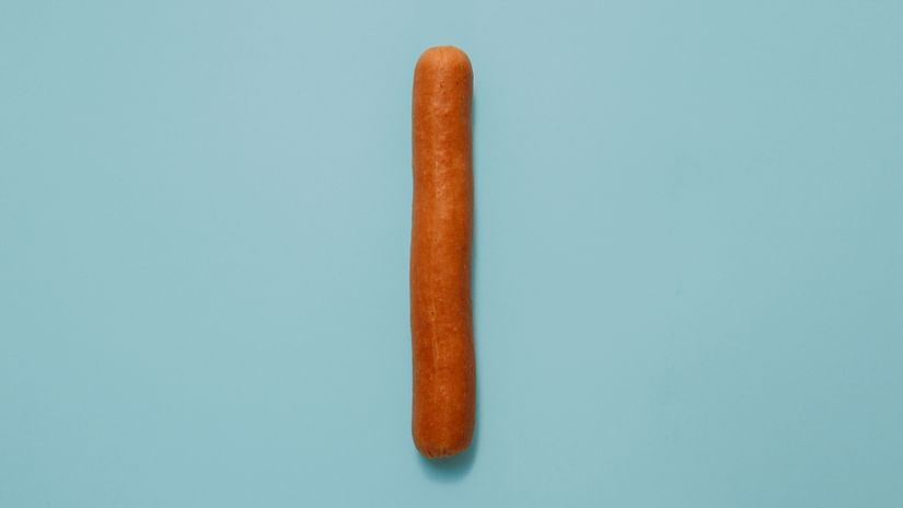 An aerial view of a single sausage kept on a a shade of blue coloured table