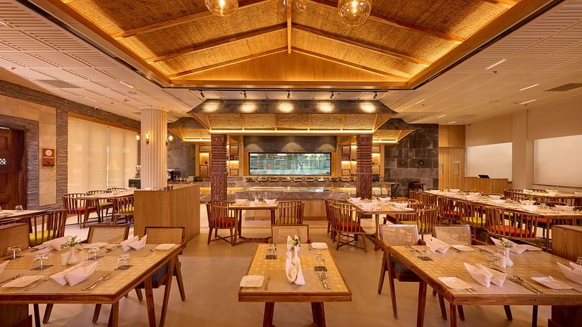 Indoor dining space with square tables and modern wooden ceiling design - Royal Tulip, Chitwan