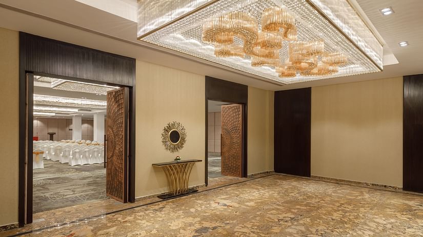 The entrance to a grand banquet hall at Royal Tulip, Kathmandu, featuring ornate doors and a stylish chandelier.