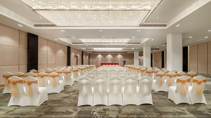 A large banquet hall at Royal Tulip, Kathmandu, prepared for an event with rows of white chairs.