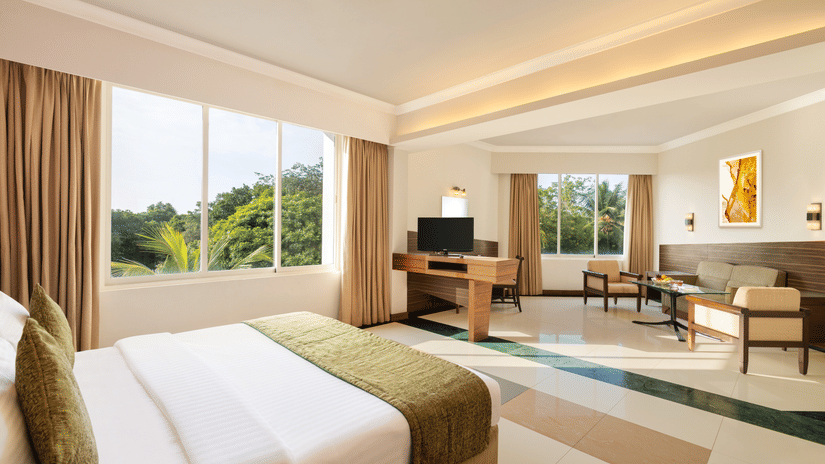A Double bed and seating arrangement inside Deluxe Room at Sangam Hotel, Thanjavur - Thanjavur Hotel Rooms