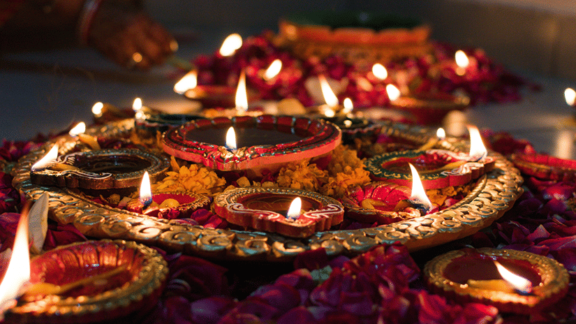 Rows of colourful oil lamps arranged on a bed of flowers during Thrikarthika