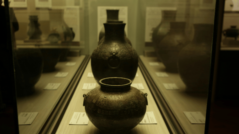 Ancient pottery vessels displayed in a glass case at a museum like those at the Pudukkottai Government Museum