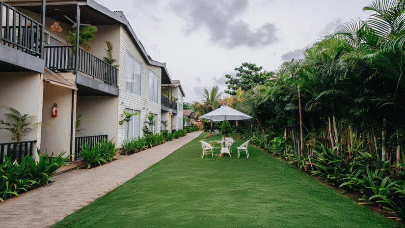 image of a lush green lawn with an outdoor seating space in the lawn that is covered with a white umbrella