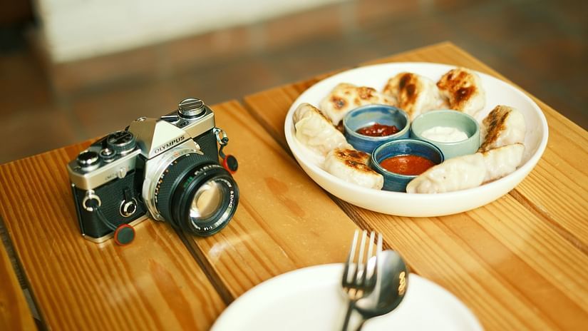 a plate of momos kept on a table next to an empty plate and a camera