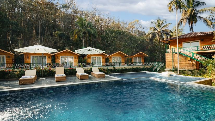 Row of cottages with loungers and a swimming pool in front of it - Stone Wood Jungle Resort, Dandeli