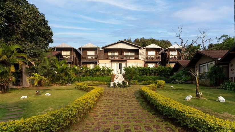 Lush garden with resort villas and statues at Stone Wood Resort, Mandrem