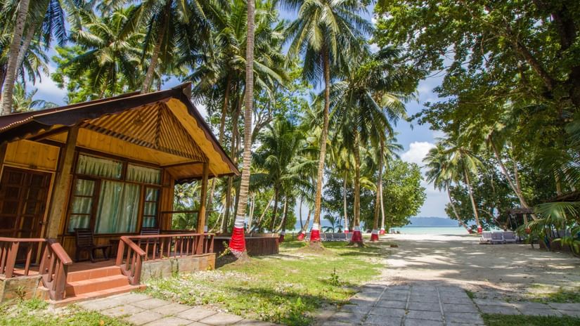 exterior facade and pathway leading to Lagoon Suite with coconut trees and the beach in the distance.