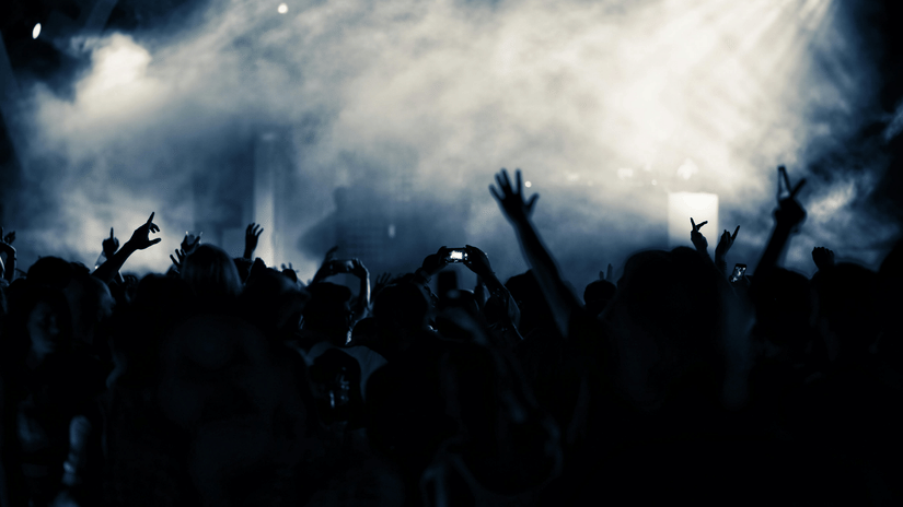A large crowd of people with their hands in the air enjoys a lively music concert.