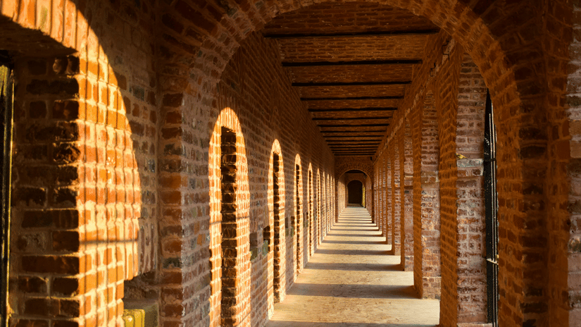 A long, vaulted brick corridor with arches receding into the distance | Cellular Jail