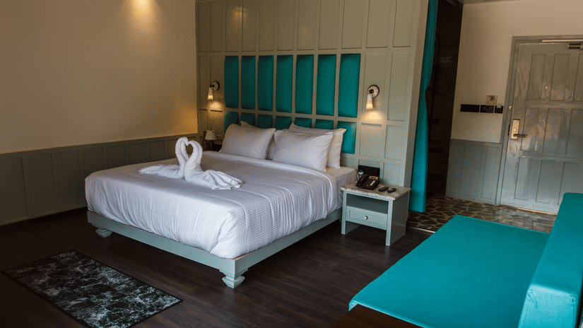 A double bed with dove towels, side stand, and lamps inside the Hill Villa at Symphony Samudra Beachside Jungle Resort And Spa, offering one of the finest Port Blair Villas.