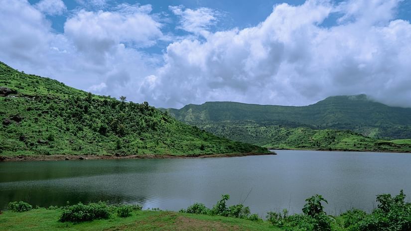 View of a lake with mountains and cloudy sky in the background.