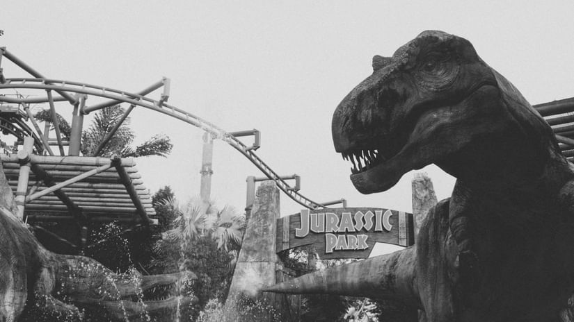 A black and white photograph of the Jurassic Park entrance at a theme park.