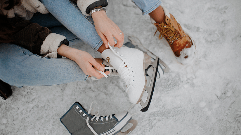 A person tying the lace of a skating shoe