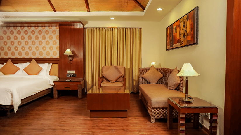 A bedroom with a king bed and a sitting area with wall mounted painting.