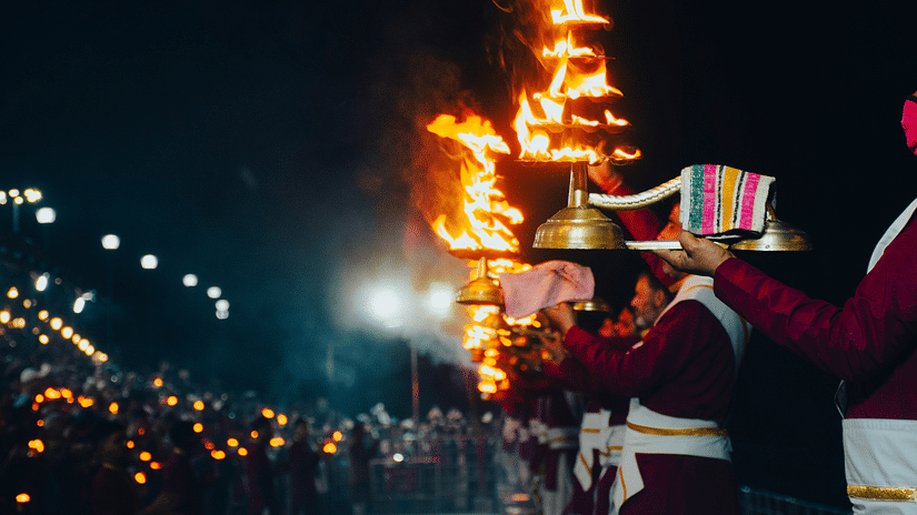 people performing Aarti at night as devotees watch on