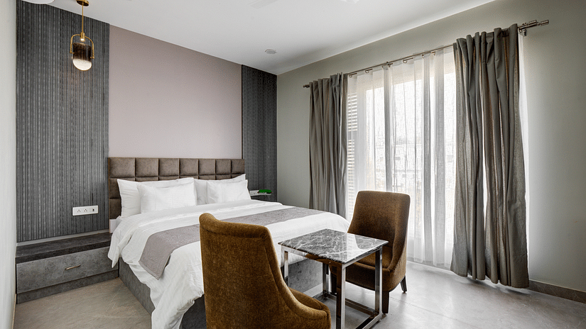 Grey themed Deluxe room with king size bed and brown chairs - The White Moon