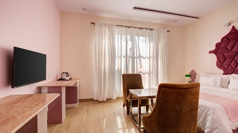 Pink themed Super Deluxe Room with king size bed, chairs and LED TV - The White Moon