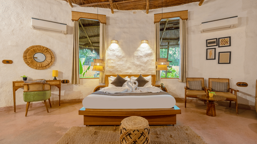 Luxurious rustic-style bedroom with wooden interiors, elegant décor, cozy bedding, and natural lighting at Themis Mudhouse - A Nature's Retreat Resort & Wellness.