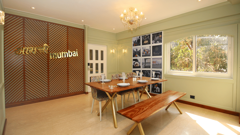 A dining space with a chair on one side and a wooden desk on the other, featuring a window at Theory9 - Premium Serviced Apartments in Bandra, Mumbai