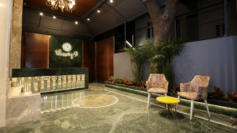 An image of a huge reception lobby  featuring a desk and two chairs with centre table at one corner - Theory9 - Premium Service Apartments, Bandra