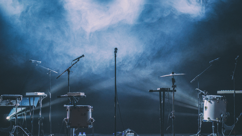 An empty concert stage with drums, microphones, and lights