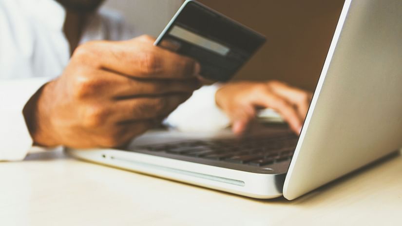 a person holding a credit card while using a laptop to make a payment for an online transaction