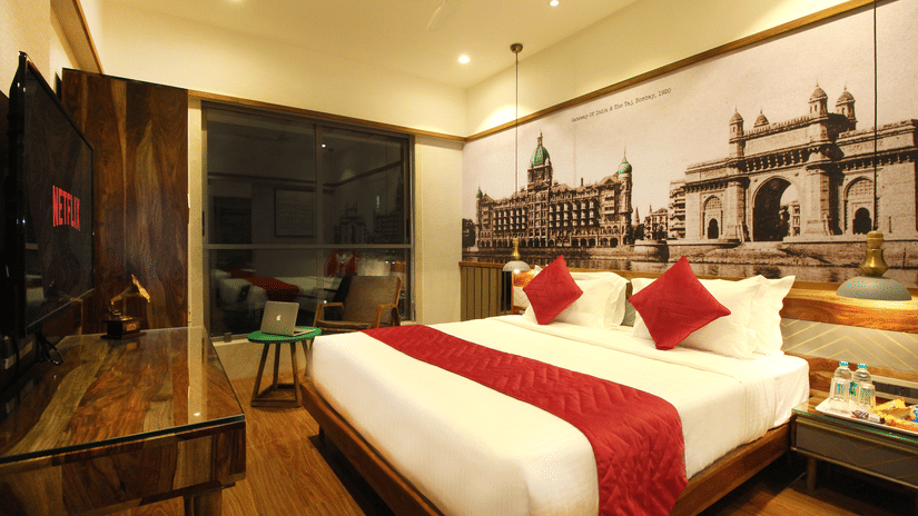 An overview of the 2 Bedroom Suite with a double bed, side tables, a tv, an expansive window overlooking the city in Khar area.