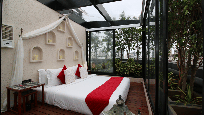 A rooftop room featuring a glass ceiling, king bed, and private open-air setting surrounded by greenery | Theory9 - Premium Serviced Apartments, Bandra