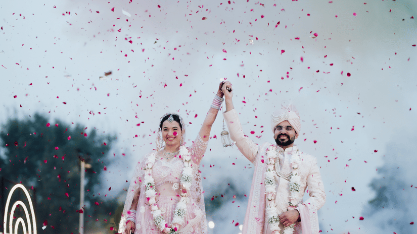 Bride and groom celebrating with confetti during a wedding ceremony at Umaid Palace.
