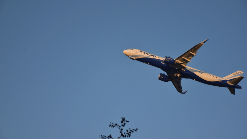 An IndiGo airplane flying in a clear blue sky during daytime.