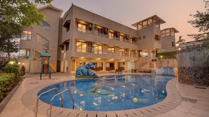 Evening view of illuminated hotel facade and pool at VITS Lonavala.