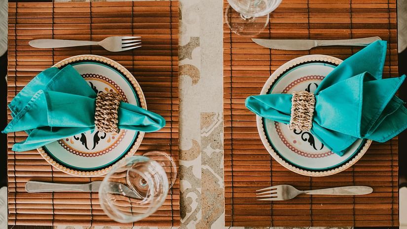 An image of a table laid out with two plates, two glasses, napkins, and cutlery