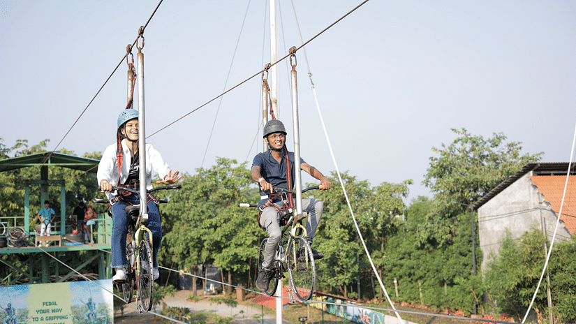 an image of two individuals performing zip cycling adventure at VITS Roccia Hill Resort & Adventure Park.