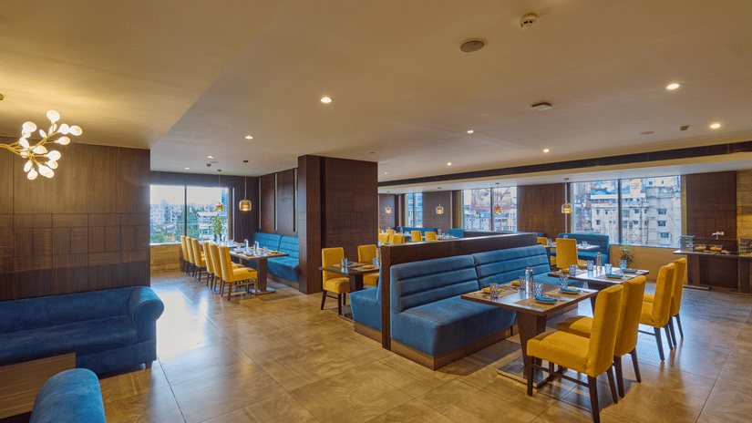 Fine dining area with velvet seating and warm wooden accents in Fine dining area with blue velvet seating and warm wooden accents in Voyage milestone hotel.