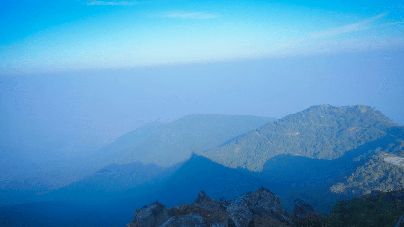 Misty mountain ranges and rocky viewpoints at Parasnath Hill overlooking the forest-covered landscape during early morning hours.