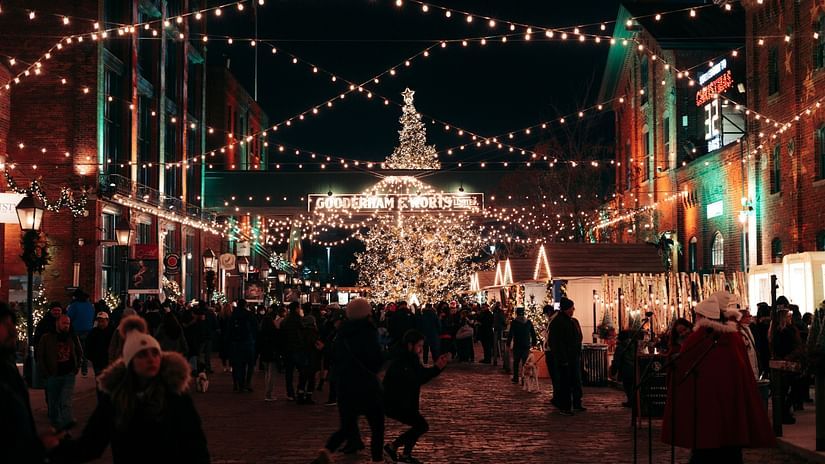 Shot of a market place decorated with colourful fairy lights and people going around.