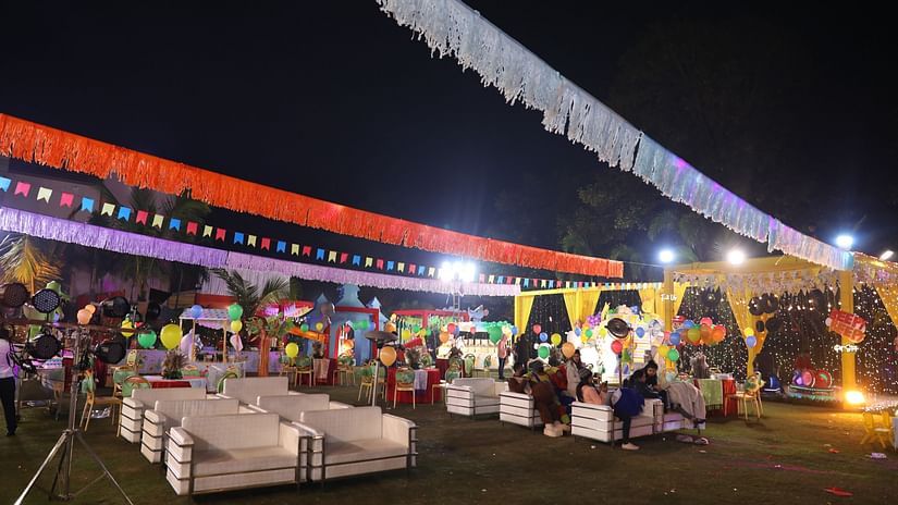 People gather in the outdoor venue, which is decorated for a celebration. - Wedlock Greens Hotel Resorts Dhanbad