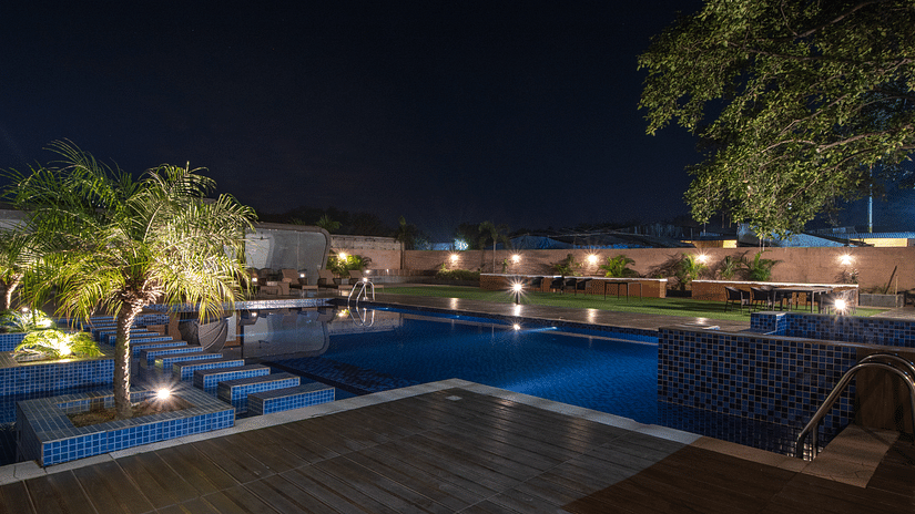 Overview of the swimming pool at night with trees near it - Wedlock Greens Hotel & resort, Dhanbad