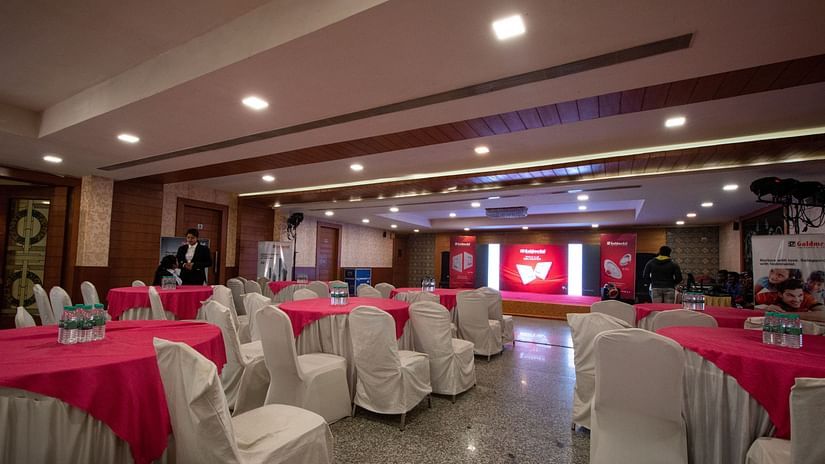 The spacious interiors of the Banquet features chairs draped in white and white & red tables - Wedlock Greens Hotel Resorts Dhanbad