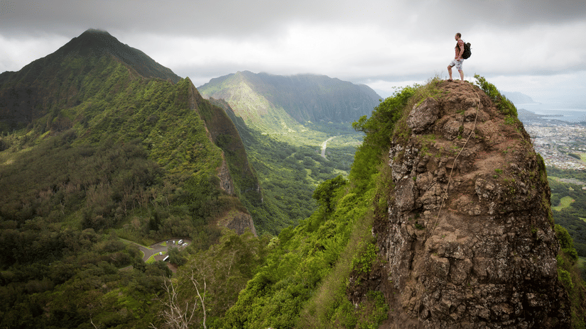 A man with a backpack standing at a mountain peak during their journey from Lonavala to Mahabaleshwar