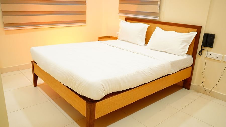 A room featuring a wooden bed, curtains and a dial phone - A M Suites