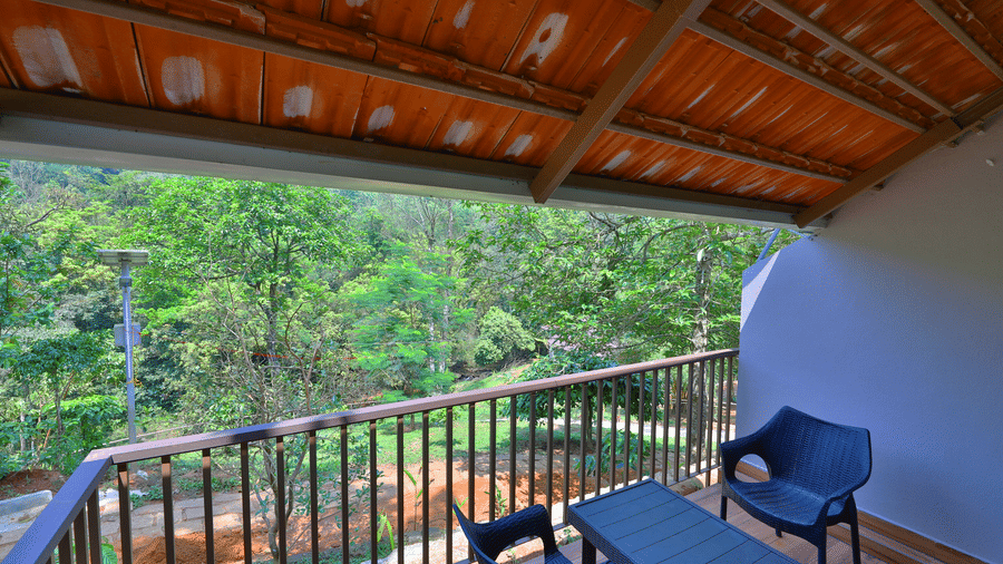 A balcony with a view of trees features a seating area, offering a relaxing outdoor space.
