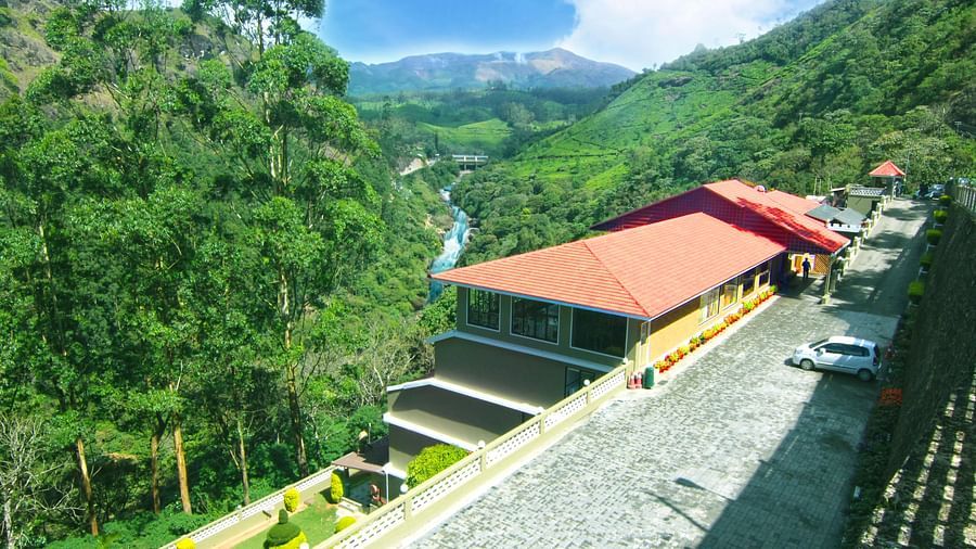 Abad Copper Castle Resort nestled in a valley with lush green hills.