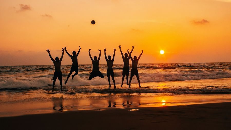 A group of men jumping for a picture with the setting sun in the background