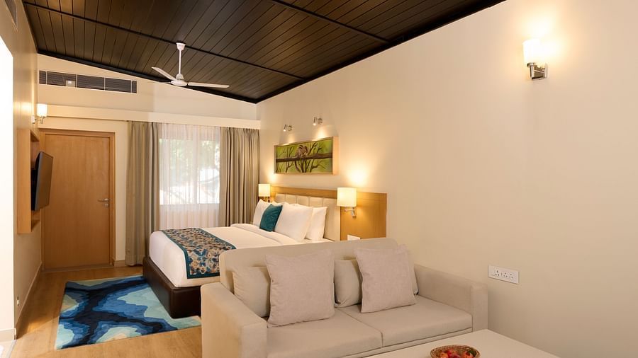 a bed, a sofa and other amenitites in the Cottage at ABN Sarovar Portico, Jim Corbett
