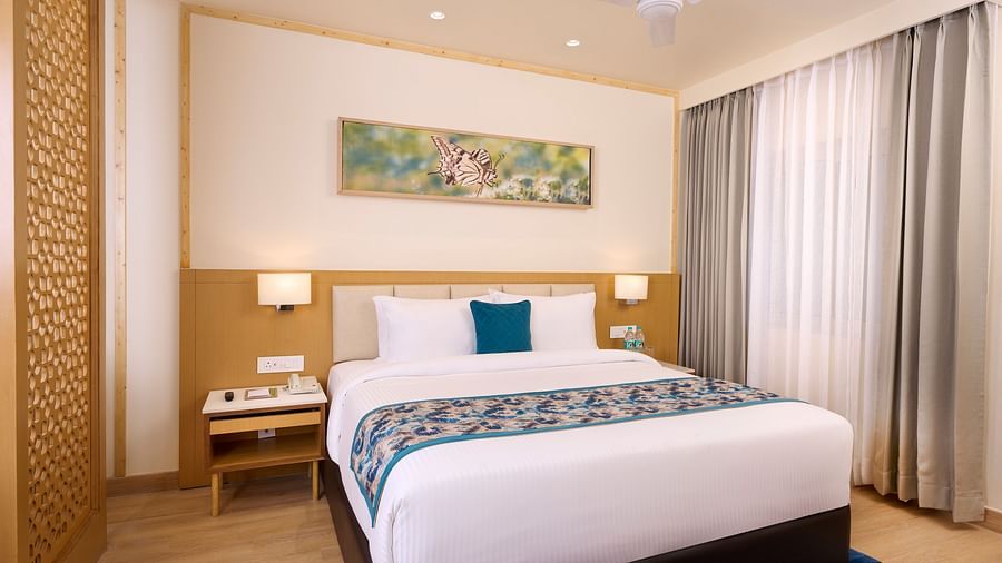 a double bed with side tables and a painting in the Cottage at ABN Sarovar Portico, Jim Corbett
