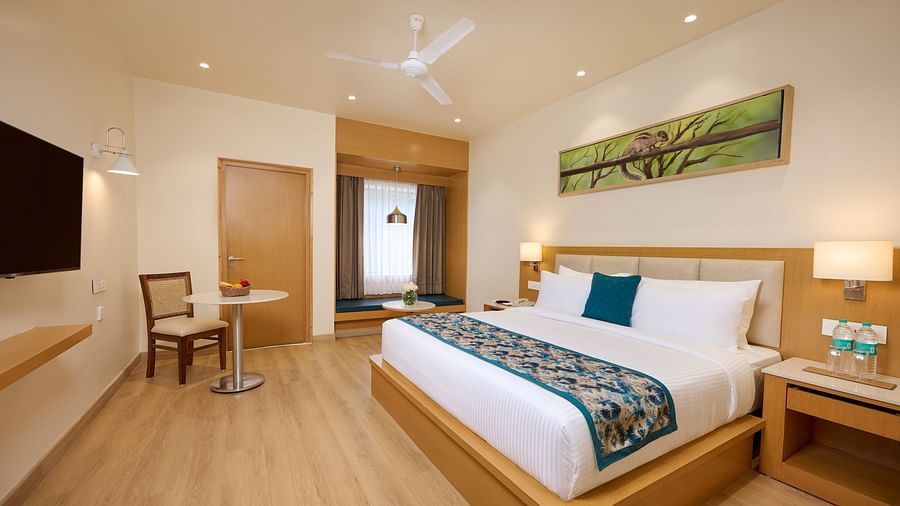 a double bed, television and the seating area of the Deluxe room at ABN Sarovar Portico, Jim Corbett